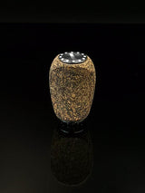 Der RL-TNG Korkknopf 20 mm | Schlank | Universal Fit von RL-Angelrollentuning ist ein kleiner, zylindrischer Knopf mit strukturiertem Korkkörper, schwarzer Oberseite und metallischen Edelstahlkugellager-Akzenten, der auf einer glänzend schwarzen Oberfläche vor dunklem Hintergrund steht.