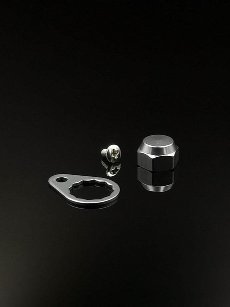 Eine RL-Angelrollentuning Kontermutter inkl. Plättchen M7 in Silber, samt flacher Metallplatte und Sechskant-Kontermutter, werden auf einer reflektierenden schwarzen Fläche dargestellt.