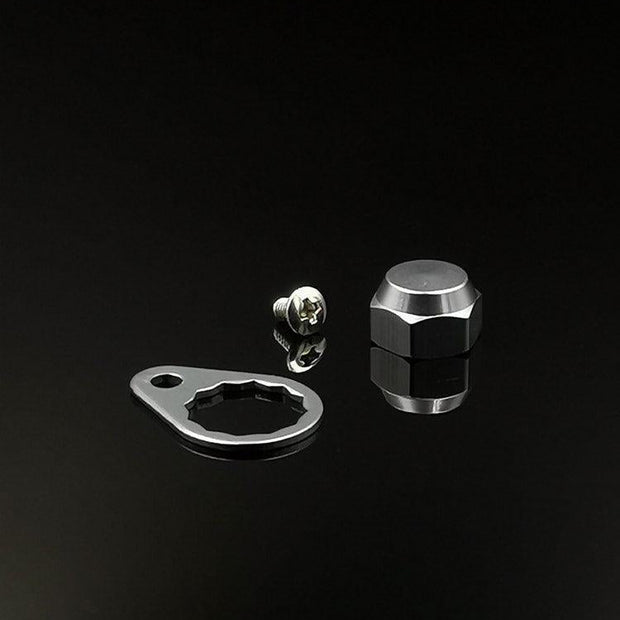 Eine RL-Angelrollentuning Kontermutter inkl. Plättchen M7 in Silber, samt flacher Metallplatte und Sechskant-Kontermutter, werden auf einer reflektierenden schwarzen Fläche dargestellt.