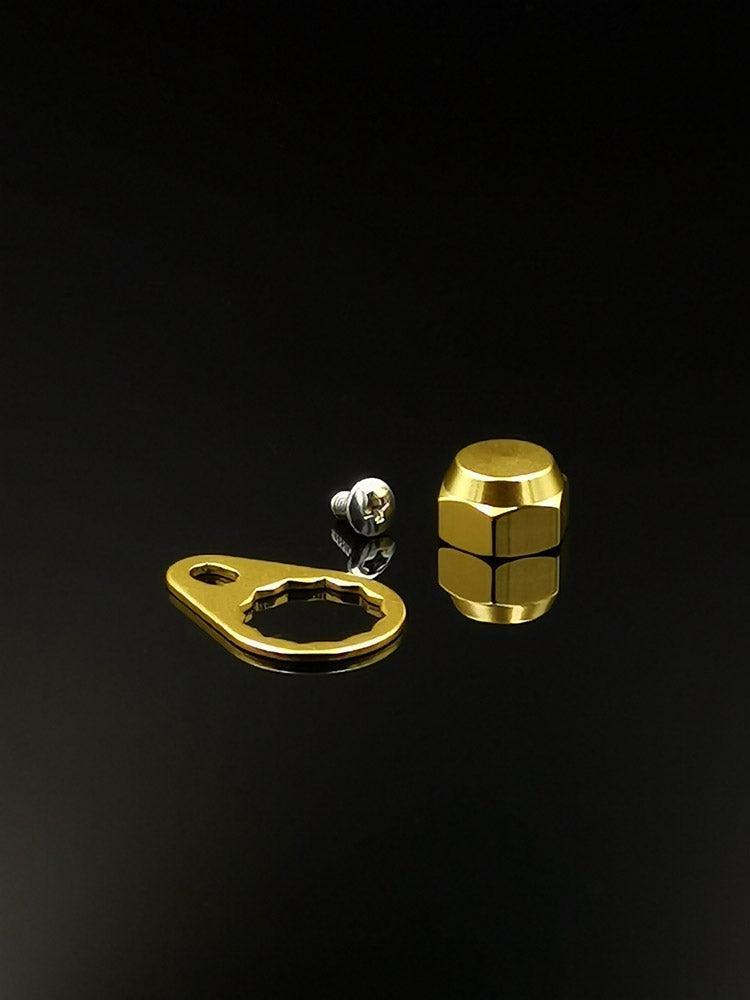 Auf schlichtem, schwarzem Untergrund sind eine goldene Kontermutter inkl. Plättchen (M7) von RL-Angelrollentuning, ein passender goldener Schraubenschlüssel und eine kleine silberne M7 Schraube abgebildet.