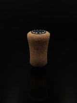 Ein einzelner RL-Angelrollentuning RL-TNG Kork-Knopf 20 mm | Griff | Universal Fit mit einer schwarz-weißen runden Oberseite steht aufrecht vor einem soliden schwarzen Hintergrund und erinnert an Details hochwertiger Angelmechanismen.