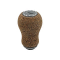 Der RL-Angelrollentuning RL-TNG Korkknopf 20 mm „Peanut“ Universal Fit verfügt über eine abgerundete Korkabdeckung, eine metallische Oberseite mit Schichtmuster und dekorative Nieten, inspiriert von Edelstahlkugellagern, isoliert auf Weiß dargestellt.
