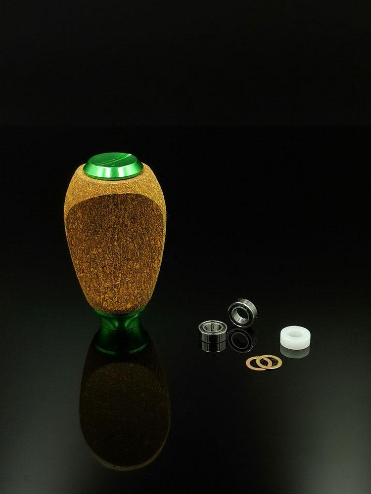 Ein RL-TNG Kork-Knopf von RL-Angelrollentuning mit mehrfarbigem Design und universeller Passform steht auf einer schwarzen Oberfläche, sein Lager, seine Unterlegscheibe, zwei kleine Ringe und ein weißer zylindrischer Abstandshalter sind ordentlich in der Nähe angeordnet.