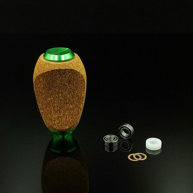 Ein RL-TNG Kork-Knopf von RL-Angelrollentuning mit mehrfarbigem Design und universeller Passform steht auf einer schwarzen Oberfläche, sein Lager, seine Unterlegscheibe, zwei kleine Ringe und ein weißer zylindrischer Abstandshalter sind ordentlich in der Nähe angeordnet.