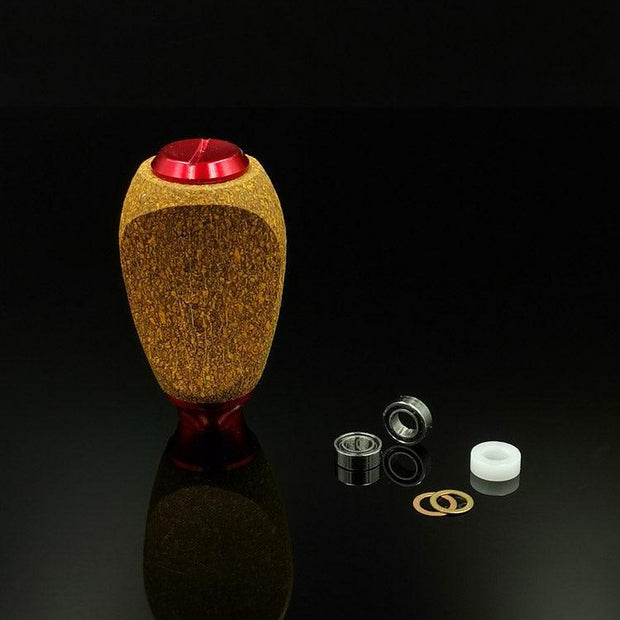 Der RL-TNG Kork Knob von RL-Angelrollentuning besticht durch seine Holzstruktur und die rote Oberseite. Er ist aufrecht auf einer schwarzen, reflektierenden Oberfläche abgebildet und mit zwei Lagern, einem weißen Abstandshalter und zwei goldenen Unterlegscheiben ausgestattet – ideal für Ihr Angelrollen-Setup.