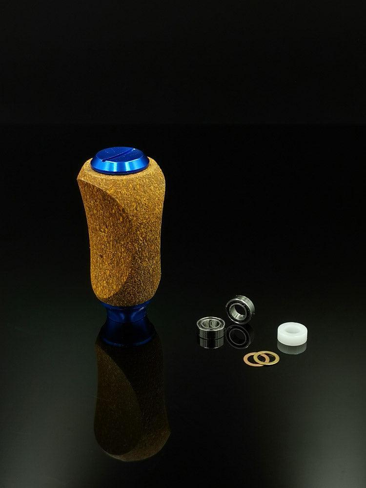 Ein RL-TNG Kork Knob von RL-Angelrollentuning aus Holz und blauem Metall steht aufrecht mit Lagern, einem weißen Abstandshalter und Unterlegscheiben auf einer schwarzen Oberfläche – ideale universell passende Komponenten für Ihre Angelrolle.