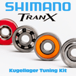 Nahaufnahme von vier verschiedenfarbigen Kugellagern mit dem Schriftzug RL-TNG Kugellager Tuning Kit für Shimano Tranx - Spulenlager & Ritzellager Upgrade by RL-Angelrollentuning oben und unten, dargestellt auf weißem Hintergrund.