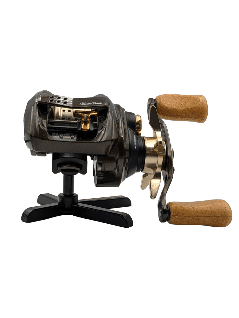 Auf dem RL-Angelrollentuning Röllenständer DK | Reel Stand sitzt eine schwarz-goldene Baitcasterrolle mit Holzgriffen und wird elegant vor einem weißen Hintergrund präsentiert.