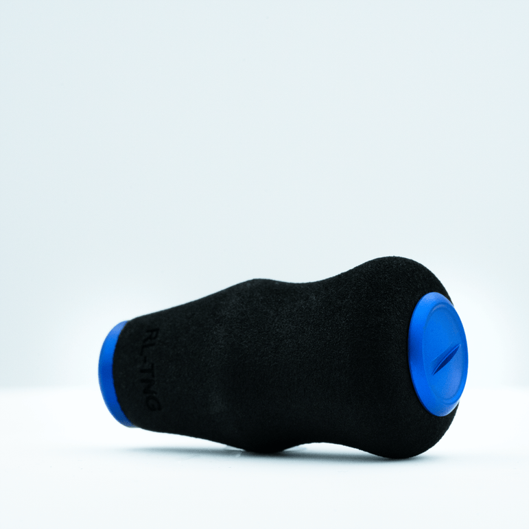Ein schwarzer RL-TNG OCT 24 EVA-Knopf von RL-TNG mit blauen, runden Enden ruht auf weißem Untergrund. Er besteht aus weichem EVA-Material, trägt den partiellen „RLTNG“-Schriftzug und verspricht maximalen Grip bei ergonomischem Design.