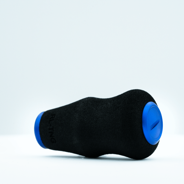 Ein schwarzer RL-TNG OCT 24 EVA-Knopf von RL-TNG mit blauen, runden Enden ruht auf weißem Untergrund. Er besteht aus weichem EVA-Material, trägt den partiellen „RLTNG“-Schriftzug und verspricht maximalen Grip bei ergonomischem Design.