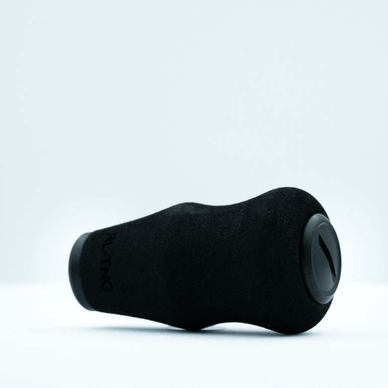 Der RL-TNG OCT 24 EVA-Knopf von RL-TNG in Schwarz mit matten und glänzenden Texturen liegt auf einer weißen Oberfläche. Seine geschwungene Form und das runde Enddetail bestehen aus EVA-Material für maximalen Grip.