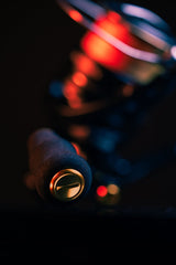 Nahaufnahme des RL-TNG OCT 24 EVA Knob-Griffs von RL-TNG mit metallischer Endkappe und EVA-Knopf vor einem dunklen Hintergrund mit rot-orangefarbener Beleuchtung; dahinter ist das verschwommene Rollengehäuse zu sehen.