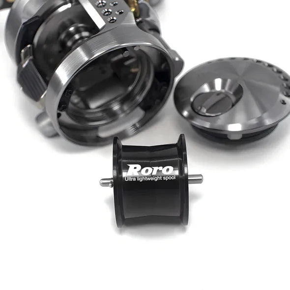 Eine Nahaufnahme einer zerlegten Angelrolle zeigt ein Metallgehäuse, eine abgenommene Abdeckung und eine schwarze Roro Lure BFS Titanium Spule CQ25-MG für 23 Calcutta Conquest BFS – ideal für Fans von Angelrollentuning-Zubehör.