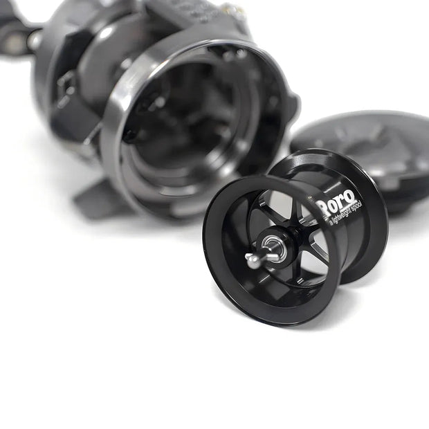 Eine Nahaufnahme einer zerlegten Roro Lure BFS Titanium Spule CQ25-MG | 23 Calcutta Conquest BFS in Schwarz, die die Hauptspule und die Innenteile auf einem weißen Hintergrund zeigt.