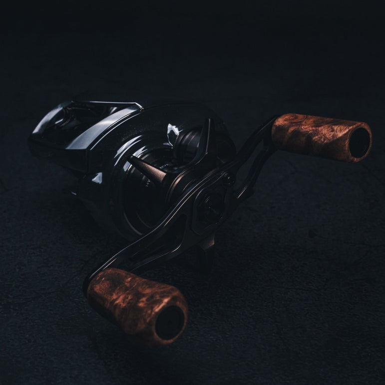 Nahaufnahme vom SLP Works i Shape Wood Knob Limited Edition – der stylische Holzgriff für deine Angelrolle! Hier liegt er richtig cool auf dunklem Untergrund, perfekt in Szene gesetzt mit dramatischer Beleuchtung. Das Must-Have für alle, die ihre Rolle individuell tunen und aus jedem Angeltag ein echtes Highlight machen wollen!.