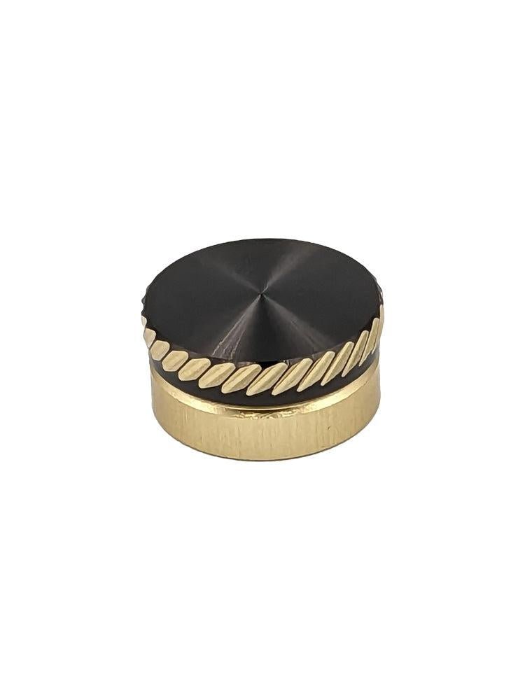 Das SLP Works MC Zero Adjuster Set von SLP Works hat einen runden, goldfarbenen Metallknopf mit schwarzer Oberseite und diagonalen Rillen. Ideal für Daiwa Baitcasting-Rollen. Fotografiert auf einem schlichten weißen Hintergrund.