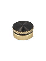 Das SLP Works MC Zero Adjuster Set von SLP Works hat einen runden, goldfarbenen Metallknopf mit schwarzer Oberseite und diagonalen Rillen. Ideal für Daiwa Baitcasting-Rollen. Fotografiert auf einem schlichten weißen Hintergrund.