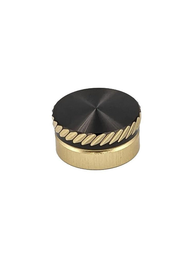 Das SLP Works MC Zero Adjuster Set von SLP Works hat einen runden, goldfarbenen Metallknopf mit schwarzer Oberseite und diagonalen Rillen. Ideal für Daiwa Baitcasting-Rollen. Fotografiert auf einem schlichten weißen Hintergrund.