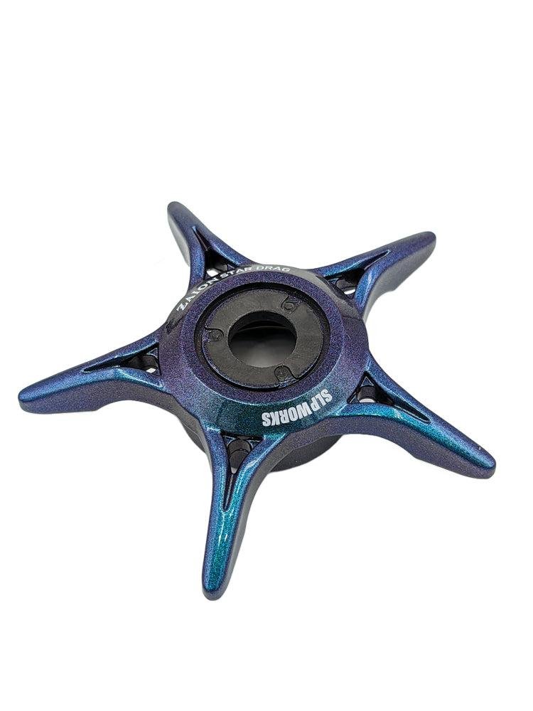 Ein Move-farbiger SLP Works Zaion Star Drag von SLP Works mit vier spitzen Armen und einem zentralen Lager mit SLP WORKS-Aufdruck, inspiriert von der Präzision der Daiwa Angelrollen, auf weißem Hintergrund.
