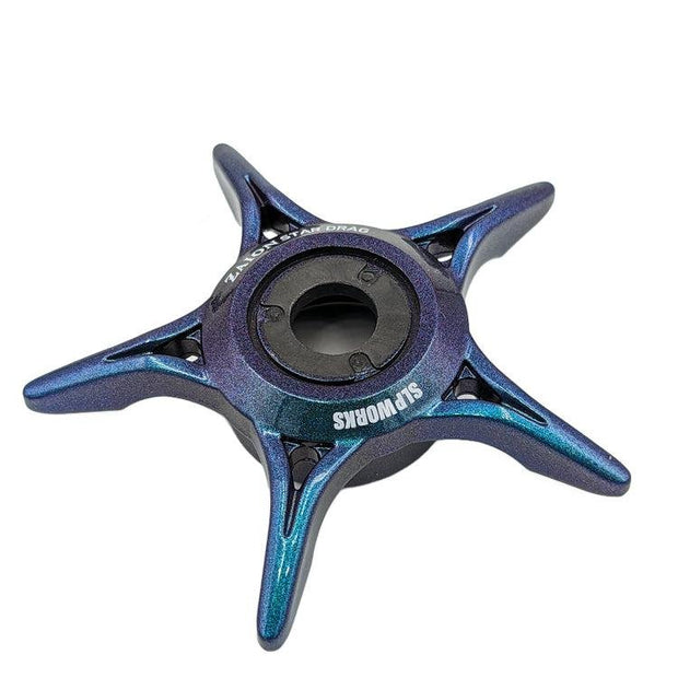 Ein Move-farbiger SLP Works Zaion Star Drag von SLP Works mit vier spitzen Armen und einem zentralen Lager mit SLP WORKS-Aufdruck, inspiriert von der Präzision der Daiwa Angelrollen, auf weißem Hintergrund.