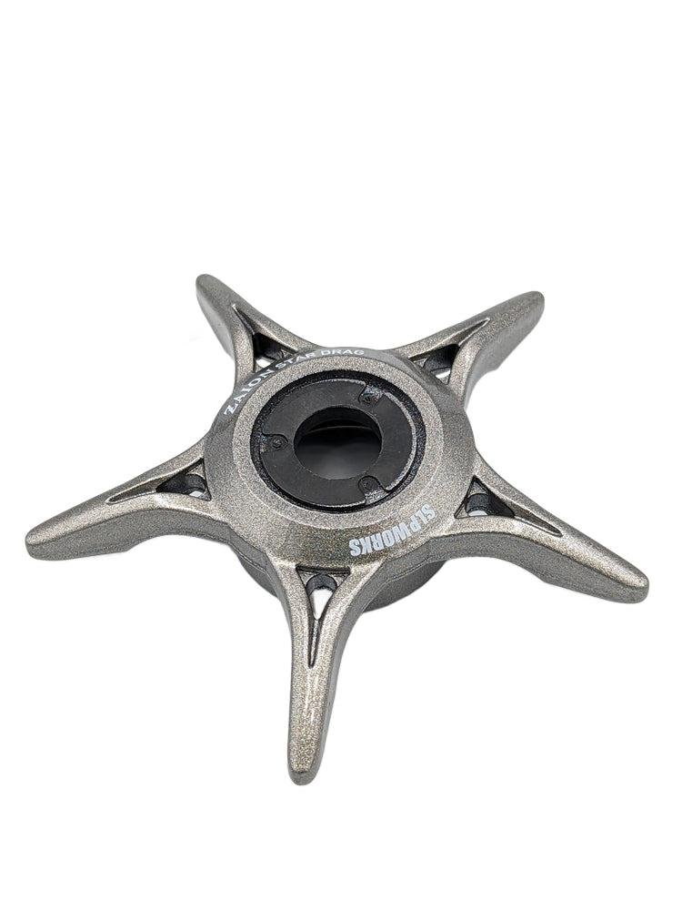 Ein silbernes, fünfzackiges Metallteil mit einem Loch in der Mitte und dem Aufdruck 