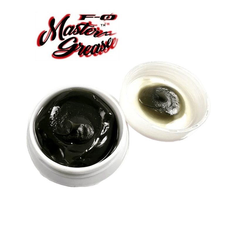 Abgebildet ist ein weißer ZPI F-Zero Master Grease | Rollenfett-Behälter mit dunklem Fett und offenem Deckel, auf dem Rückstände zu sehen sind, mit dem Master Grease-Logo darüber auf weißem Hintergrund.