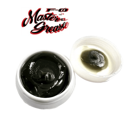 Abgebildet ist ein weißer ZPI F-Zero Master Grease | Rollenfett-Behälter mit dunklem Fett und offenem Deckel, auf dem Rückstände zu sehen sind, mit dem Master Grease-Logo darüber auf weißem Hintergrund.