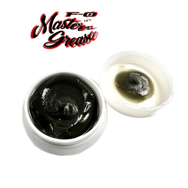 Abgebildet ist ein weißer ZPI F-Zero Master Grease | Rollenfett-Behälter mit dunklem Fett und offenem Deckel, auf dem Rückstände zu sehen sind, mit dem Master Grease-Logo darüber auf weißem Hintergrund.