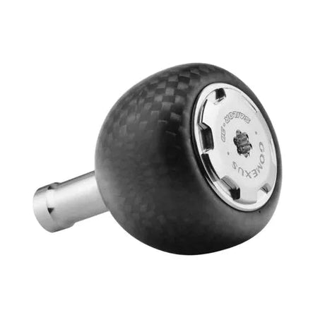 Der Gomexus Carbon Power Knob 38 mm ist ein schwarz strukturierter Lenkradknauf für Autos mit einer silbernen Metallbasis und einer runden silbernen Platte oben, auf der in der Mitte der Markenname und das Logo von Gomexus zu sehen sind.