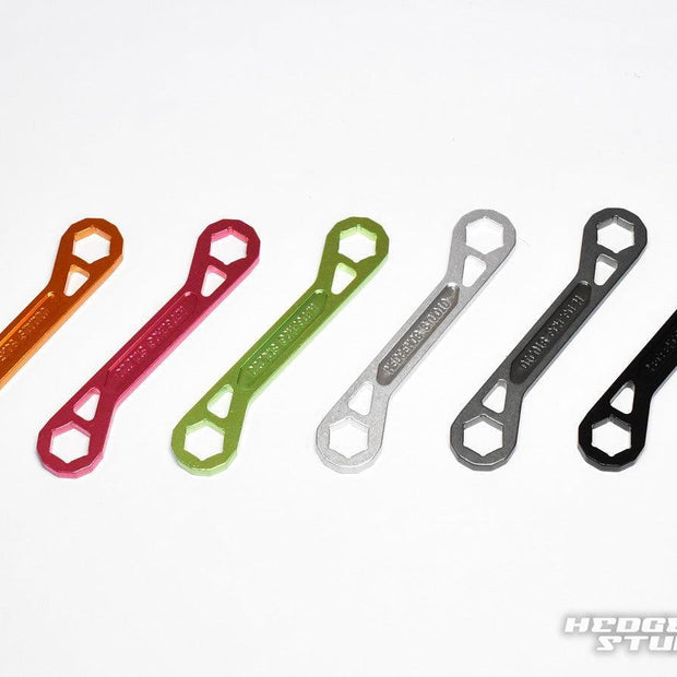 Sechs doppelseitige Schlüssel (Lock Nut Schlüssel) des Hedgehog Studio Trust Wrench Ver.3 – orange, rot, grün, silber, grau und schwarz – sind auf weißem Grund angeordnet. Alle haben die gleiche Form; das Hedgehog Studio-Logo erscheint unten rechts.