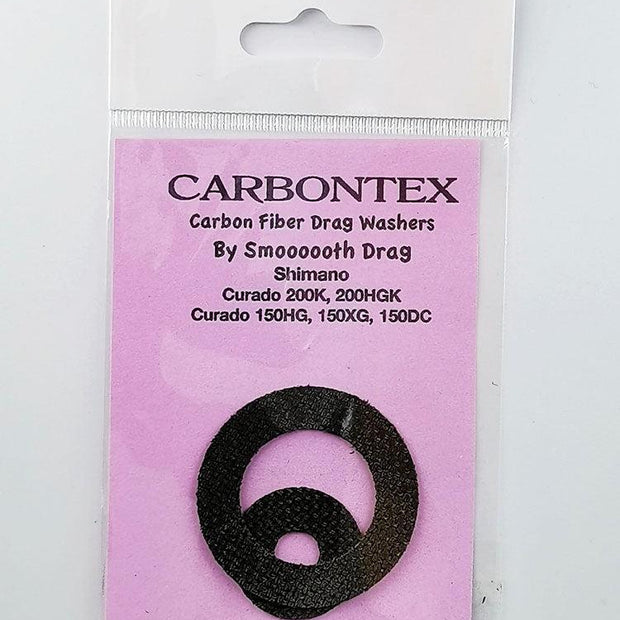 Ein Smoothdrag Bremsscheiben Carbontex-Pack für Shimano Baitcasterrollen enthält zwei schwarze runde Scheiben, die auf einem rosa Hintergrund in einer durchsichtigen Kunststoffverpackung abgebildet sind, und verspricht eine verbesserte Bremskraft für Ihre Angelrolle.